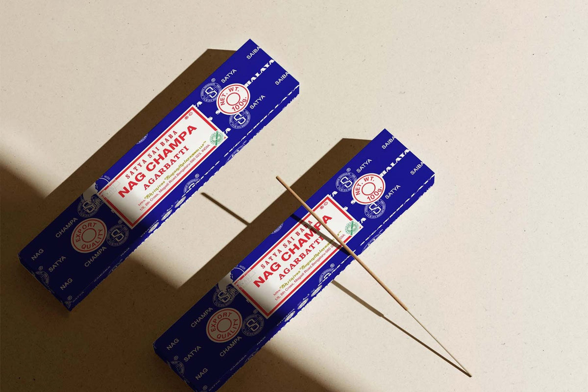 Satya Nag Champa incense boxes with a lit stick