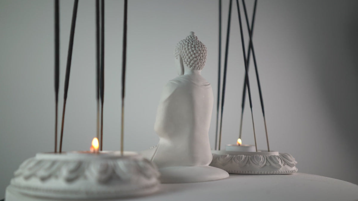 Fumino incense sticks burning beside a white Buddha statue