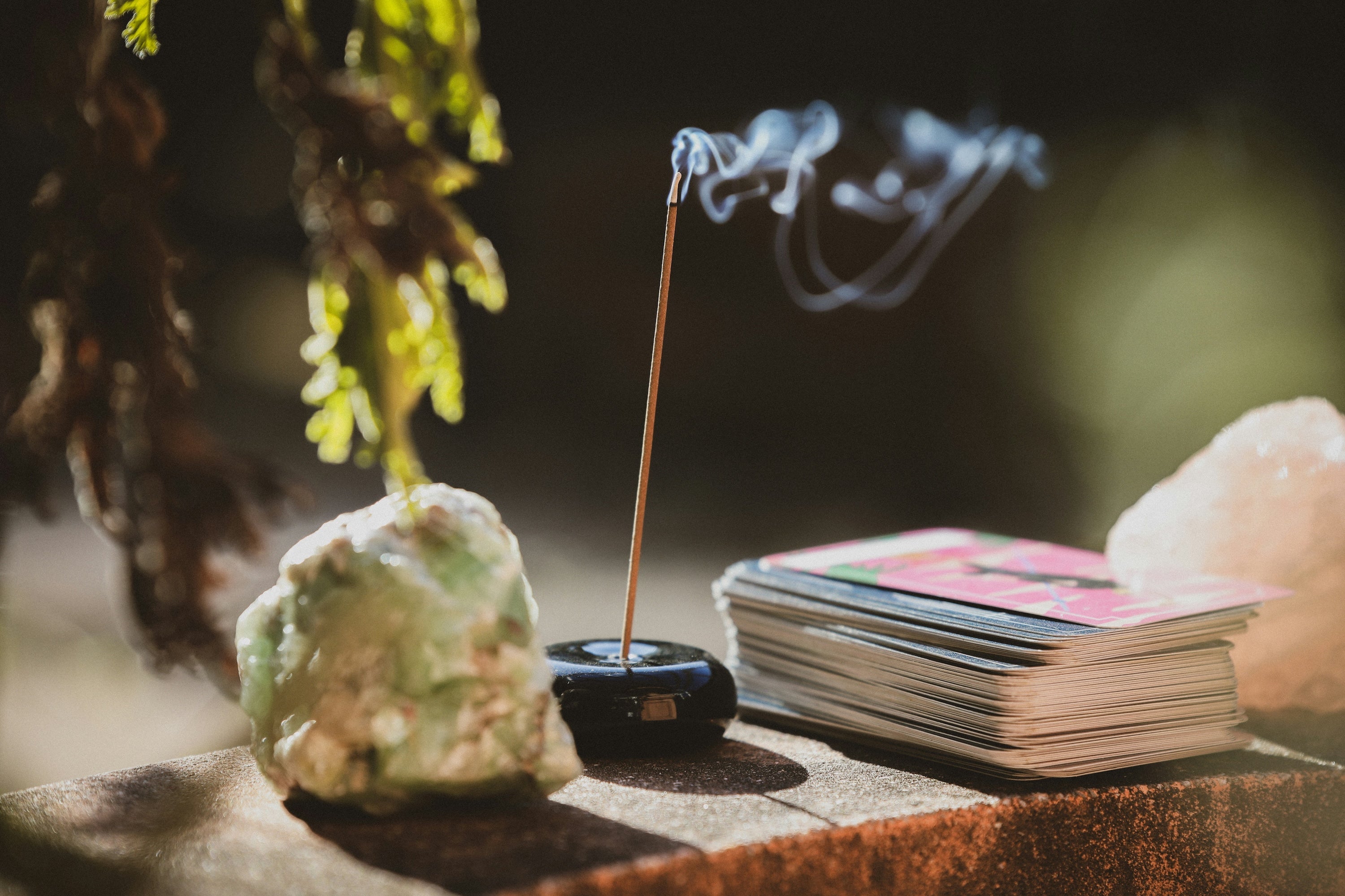 A single incense stick burning in a small holder in warm afternoon light